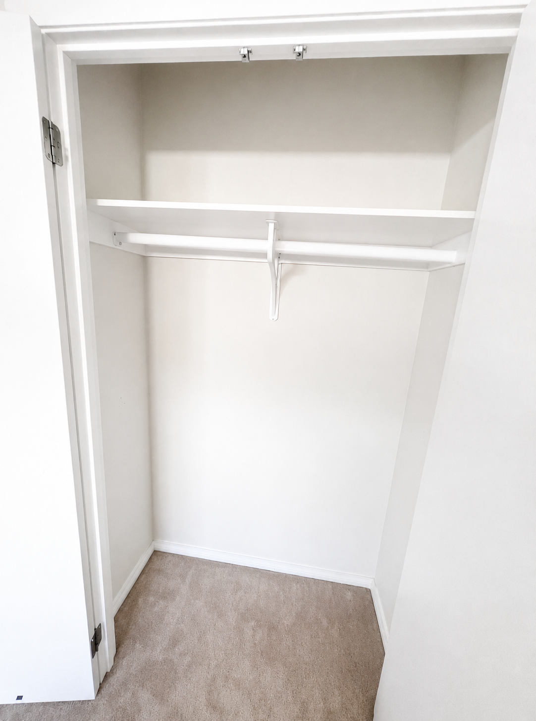 White built-in wardrobe interior with shelving and hanging rail